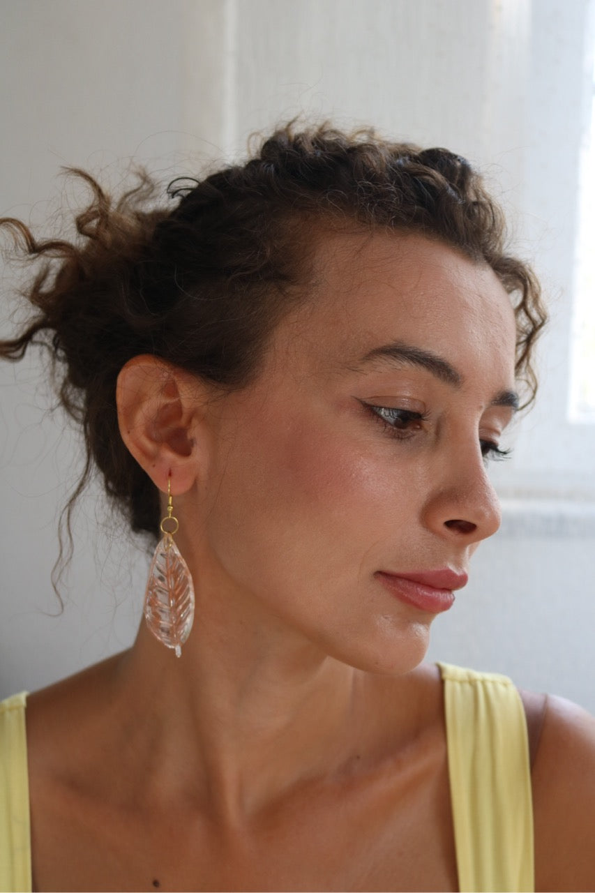 Woman wearing a yellow top and earrings with a neutral background
