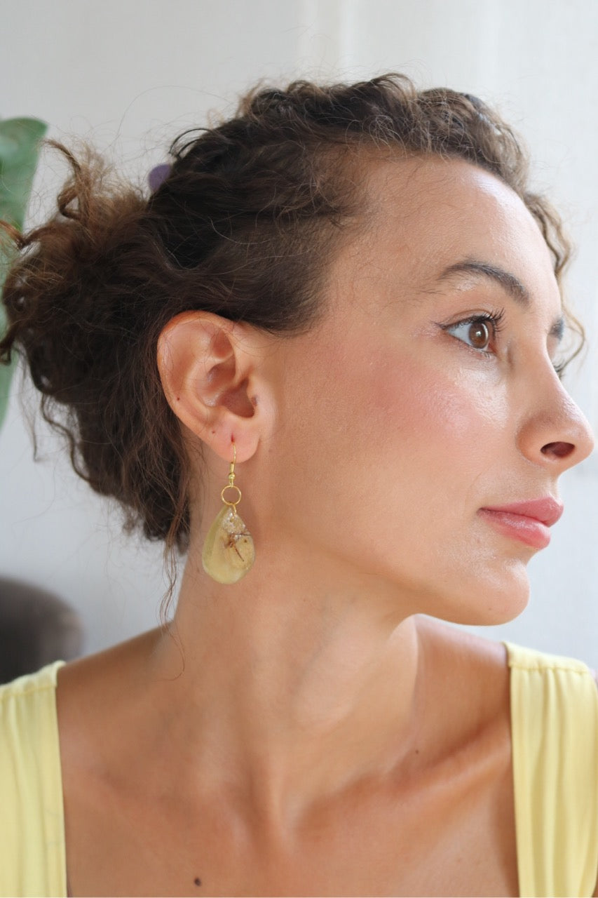 Woman wearing a yellow top and earrings with a blurred background