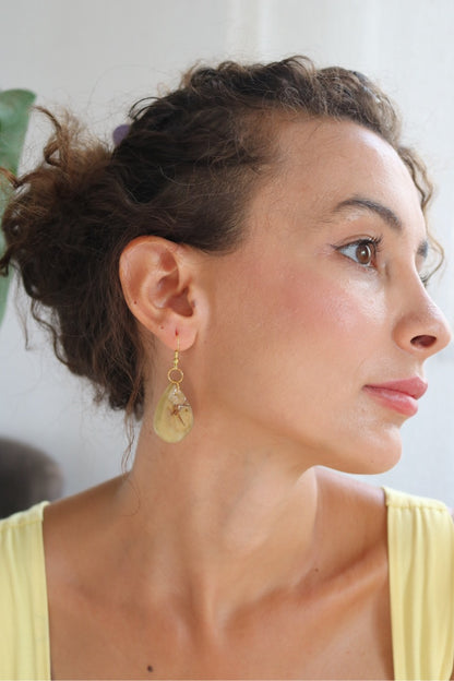 Woman wearing a yellow top and earrings with a blurred background