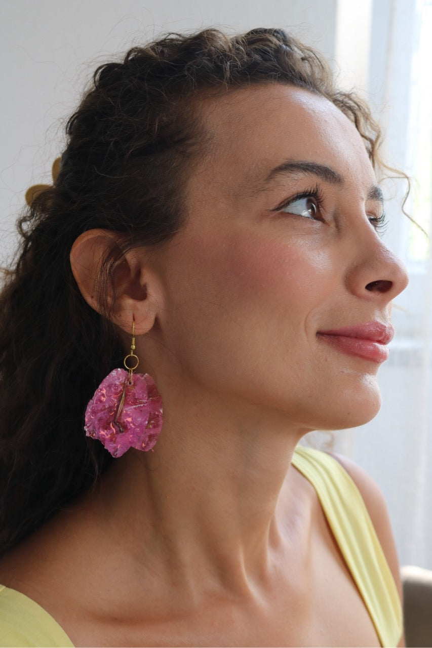 Woman wearing pink earrings, looking to the side with a neutral expression.