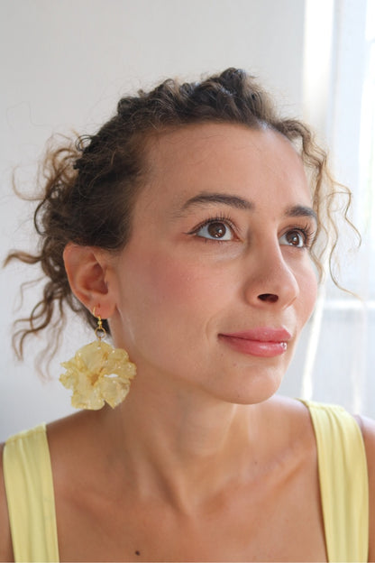 Woman wearing yellow earrings with a neutral background