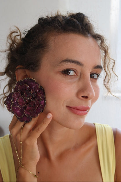 Woman wearing a large purple flower earring indoors