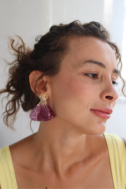 Woman wearing purple earrings with a neutral background