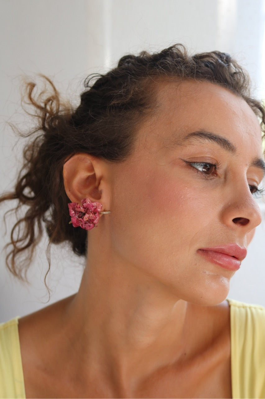 Woman wearing pink floral earrings with a neutral background